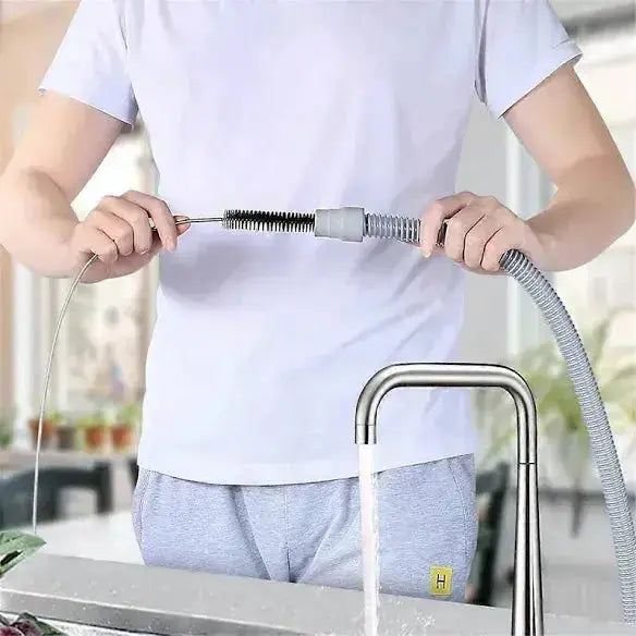 Person using a flexible hose with a brush attachment over a faucet in a kitchen setting.