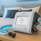 Philips Trilogy EVO ventilator machine on a nightstand with a bedroom-CPAPSupply UK background